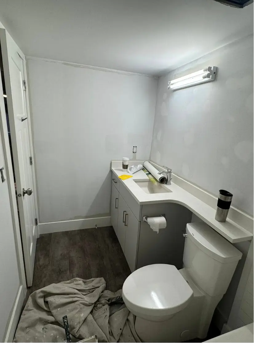 Bathroom under construction with toilet, sink, and mirror.