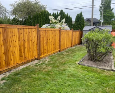 Tall wooden fence in a well-maintained backyard with lush green lawn.