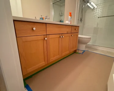 Bathroom with toilet and sink, tarp covering floor during remodeling.