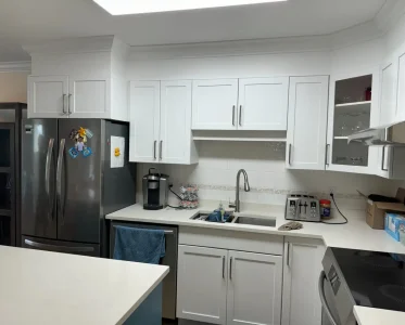 Clean kitchen with white cabinets, appliances, and dining table