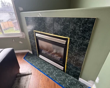 A living room with a black and gold tile fireplace and comfortable seating.
